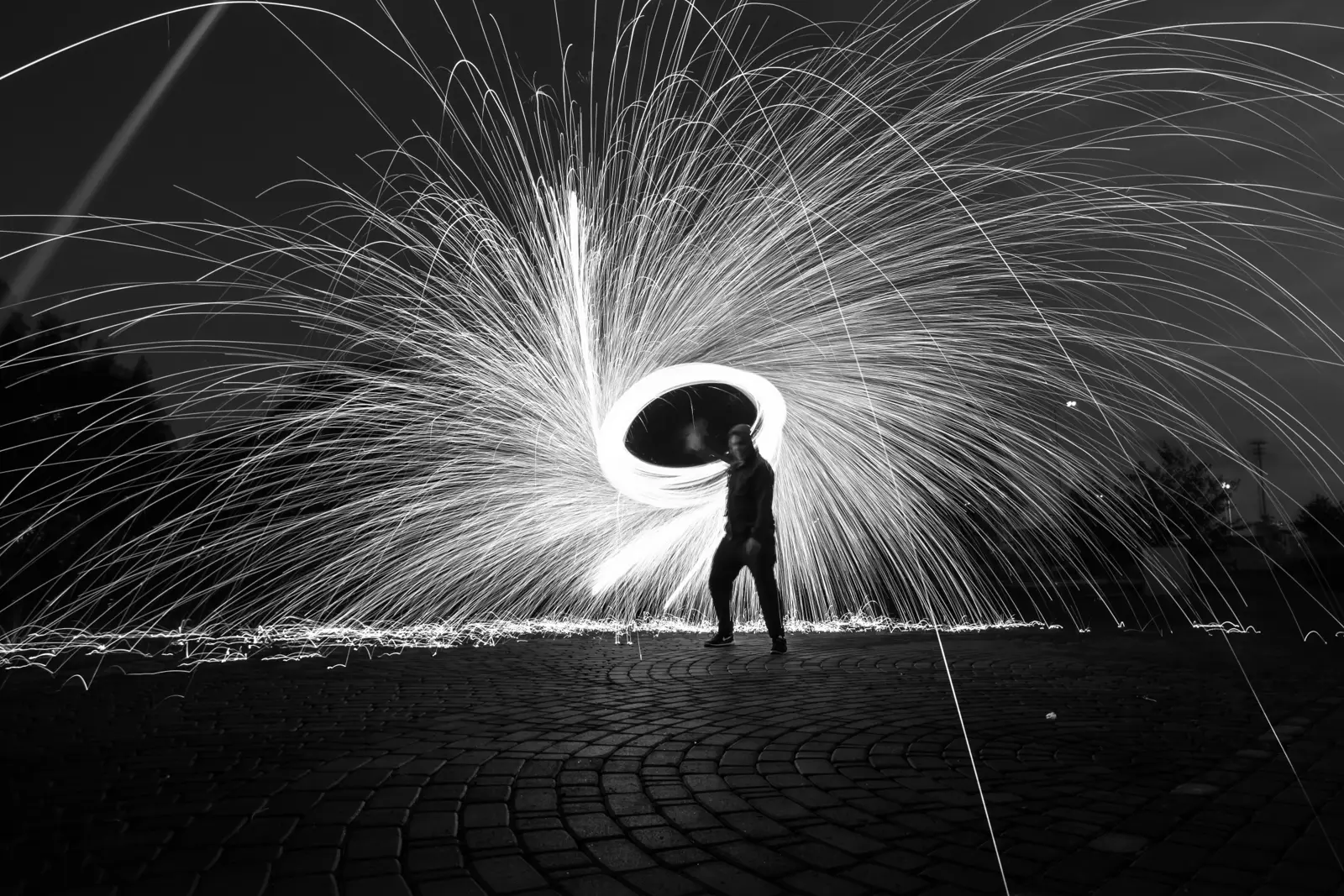 Oliver Granlund flinging burning steel wool, photographed with long shutter speed